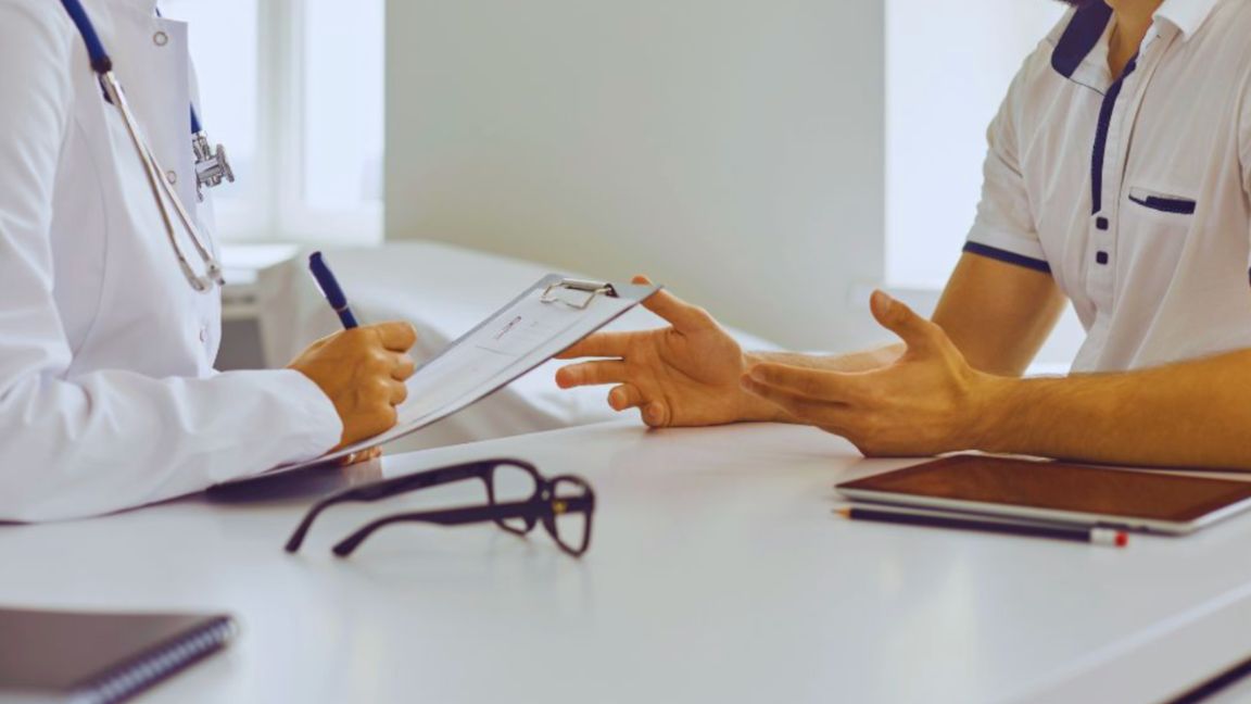 Men’s Wellness: Why Is It Important In A Man’s Life? 3 A male patient consulting with a healthcare professional who is taking notes on a clipboard, highlighting personalized men’s wellness services in Miami, FL, focused on preventive care and health planning.