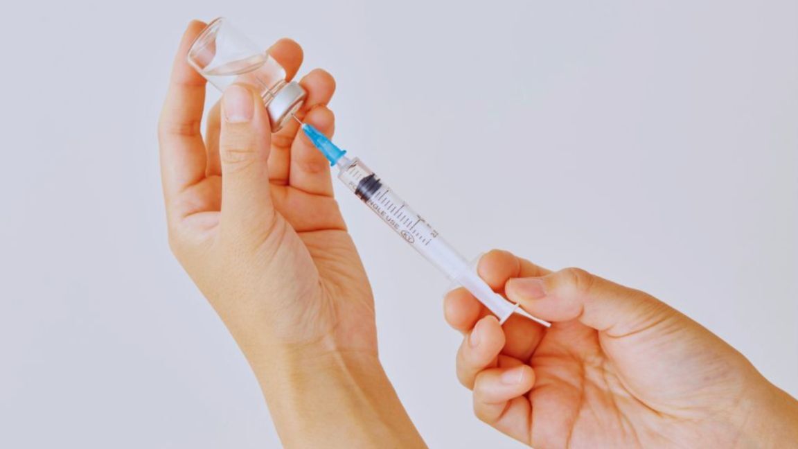 The image shows a person’s hands holding a vial and drawing a clear liquid with a syringe, representing the use of injectable peptides for injury recovery.