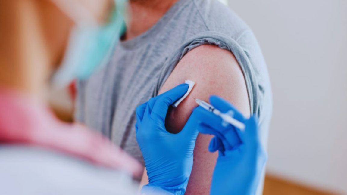 A healthcare provider wearing blue gloves prepares to inject a patient’s upper arm with a syringe, symbolizing the use of peptides for injury recovery.