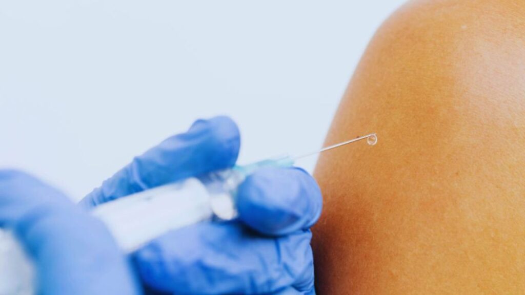 A close-up image of a healthcare professional wearing blue gloves administering an injection into a person’s upper arm, representing the medical use of nootropic peptides for supporting brain health and cognitive function.