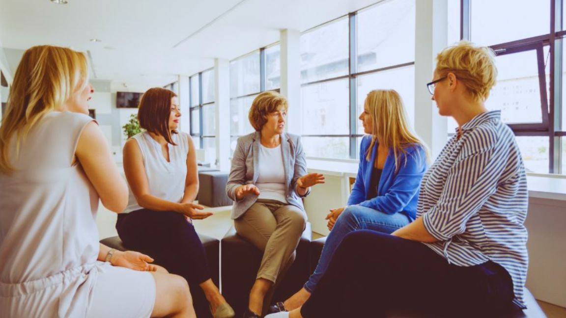 Group of women in a modern wellness space discussing women’s health, awareness, and preventive care.