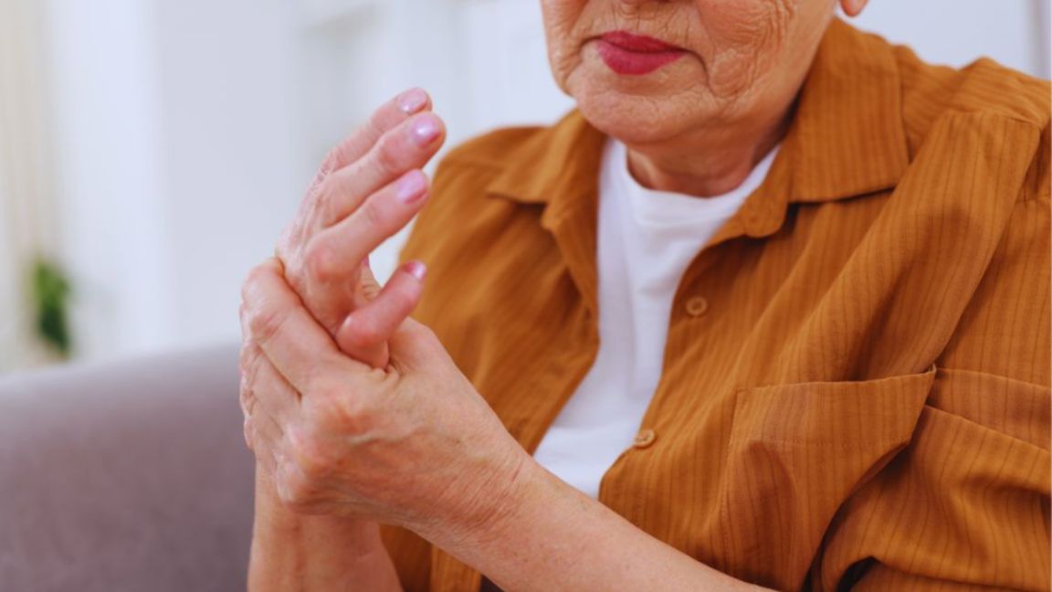 Close-up of an older adult holding and rubbing a painful hand, illustrating chronic pain, joint discomfort, arthritis symptoms, and reduced hand mobility.