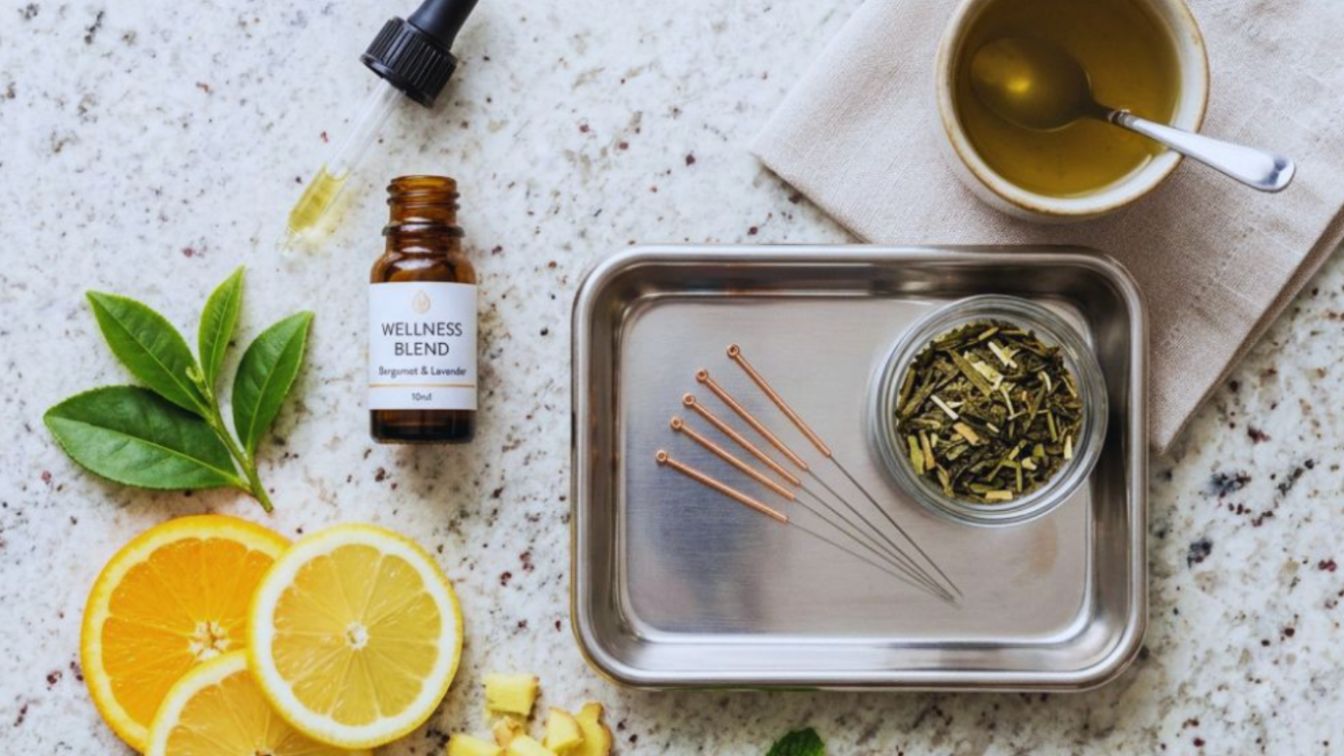 An overhead view of holistic wellness items, including acupuncture needles, herbal remedies, and nutrition support tools.